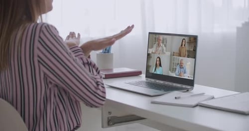 Vue arrière d'une employée parlant lors d'un appel vidéo avec divers collègues multiraciaux en ligne