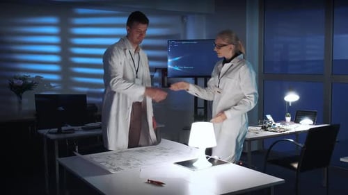 Scientists Collaborate in Dimly Lit Office at Night