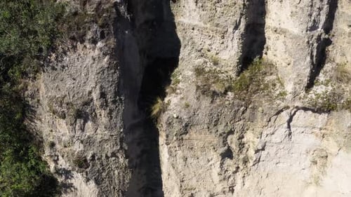 Langsam nach oben bewegt, zeigt sich eine große, felsige, graue Klippe mit sehr wenigen Pflanzen.