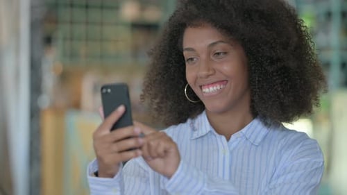Woman Smiling and Using Her Smartphone Indoors