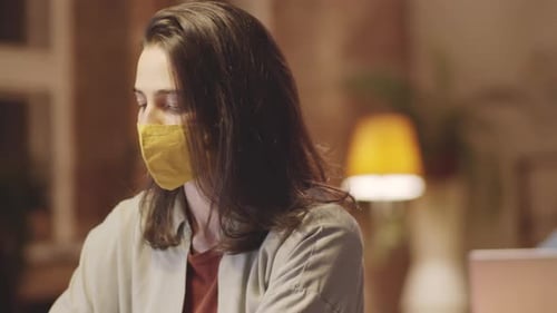Young Office Workers in Protective Masks Using Laptops at Desks