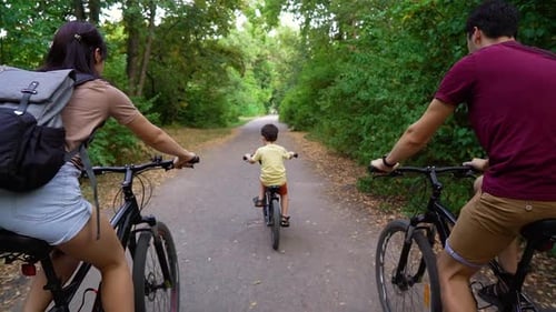Little boy and parents biking in park on summer day