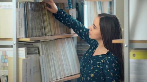 Pretty Female College Student in a Library Looking for a Book