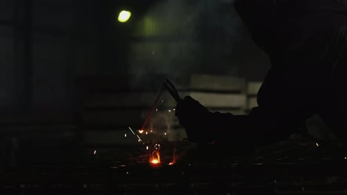Welder Working with Metal in Dark Factory