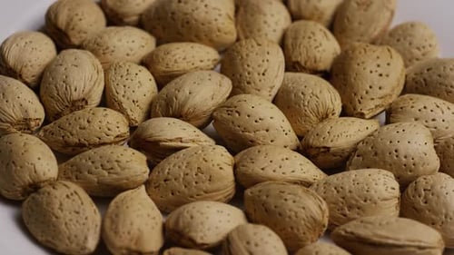Cinematic, rotating shot of almonds on a white surface