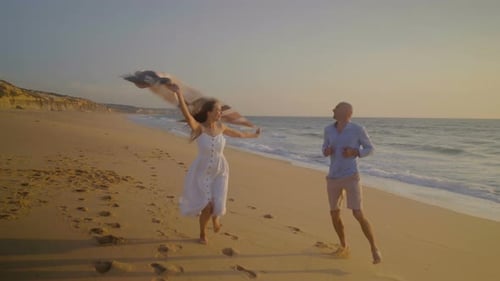 Happy Couple Running on Beach at Sunset