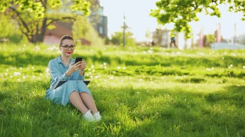 Mujer usando un teléfono inteligente mientras está sentada en el parque después de terminar su trabajo