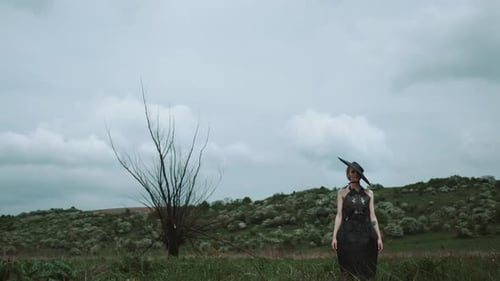 Woman in Black Dress Stands in Rural Field