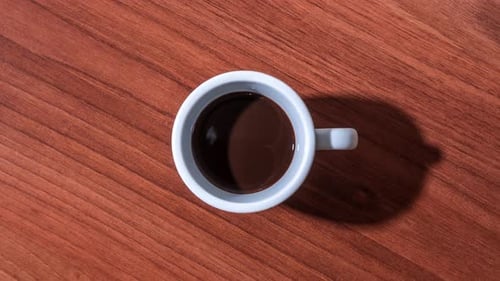 Coffee being poured into white mug on wood surface