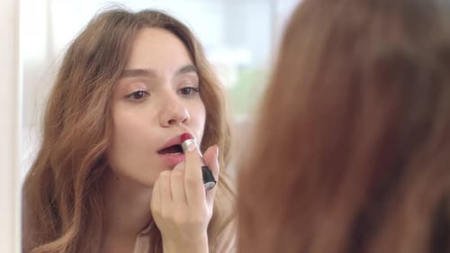 Schöne Frau mit Lippenstift für Lippen-Make-up-Frontspiegel im Badezimmer
