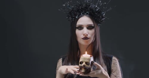 Woman with Dark Makeup Holding Skull Candle
