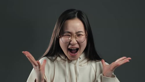 Young Frightened Screaming Asian Girl Shocked Isolated Over Grey Background.