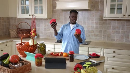 Heureux homme afro-américain choisissant de la confiture maison dans la cuisine en souriant posant à la maison