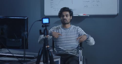 Man in Wheelchair Vlogging at Computer in Office