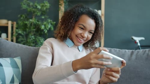 Woman Smiling Playing a Game on Smartphone