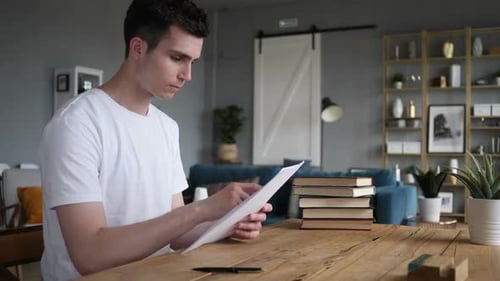 Young Man Reviews Documents at Wooden Table