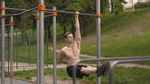 Young Caucasian Athlete with Muscular Torso Doing Corner on Crossbar
