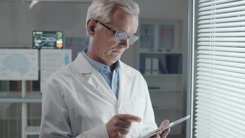 Senior Male Doctor Using Digital Tablet in Medical Office
