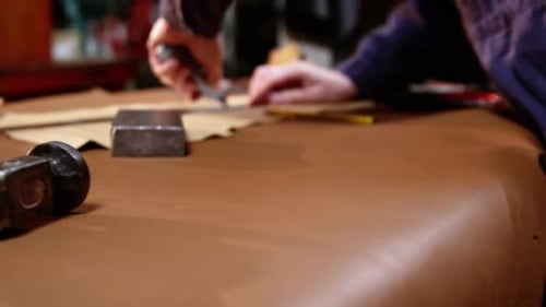 Schuhmacher schneidet ein Stück Leder