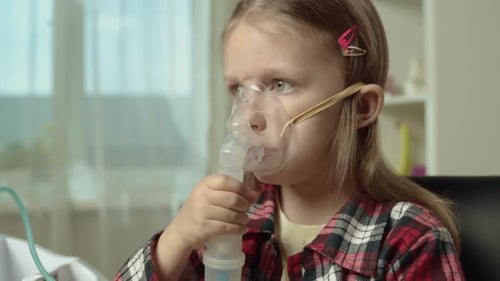 Niña hace inhalación en mascarilla facial con nebulizador.