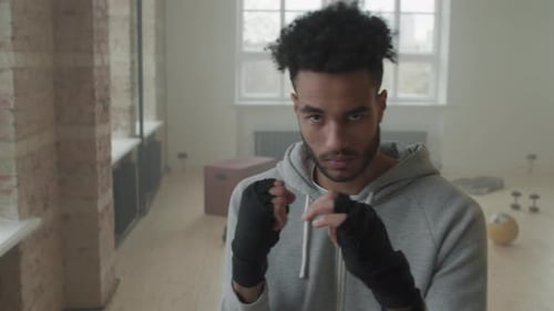 Man with Boxing Wraps Fists Up Indoors