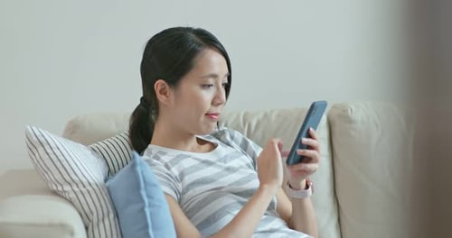 Woman Using Smartphone on Couch at Home