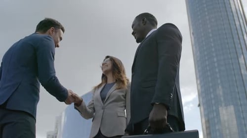 Businessman Greeting Colleagues with Handshake Outdoors