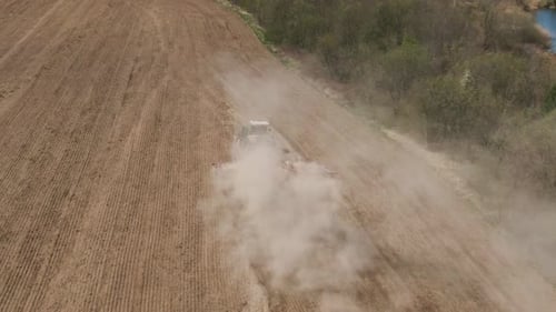 Aerial Top View of Tractor Cutting Furrows in Farm Field for Sowing Farm Tractor with Rotary Harrow
