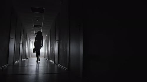Woman Silhouette Walking in Dark Hallway at Night