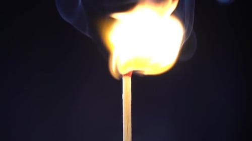 Burning Matchstick Against Dark Background