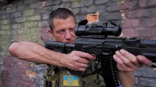 Der ukrainische Soldat zielt mit seinem Sturmgewehr mit Schalldämpfer