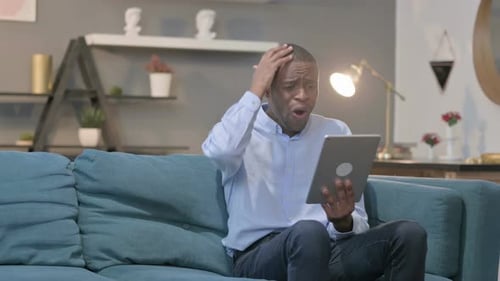 Man Using Tablet Looks Distressed at Home