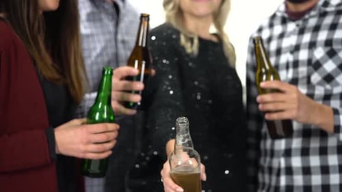 A Group of Friends Clink Glasses with Beer Bottles