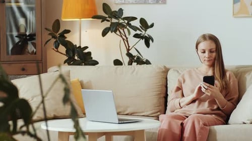 Woman on Sofa Using Smartphone in Home Setting