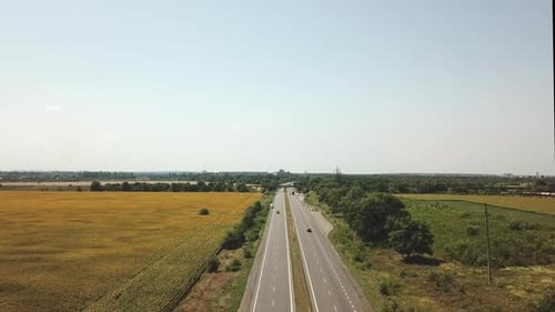 Blick aus der Luft mit Hilfe einer Drohne auf der Straße mit einem fahrenden Auto in einer bergigen Gegend.