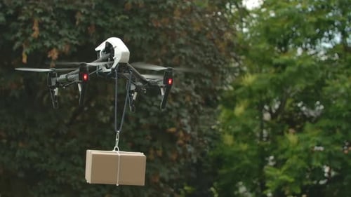 Drone Delivering Package over Green Trees