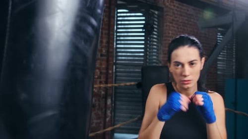 Female Boxer Punches Punching Bag in Gym