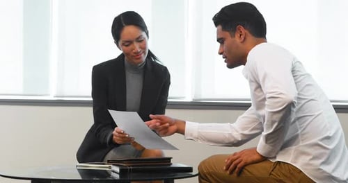 Man and Woman Discussing Documents in Corporate Setting