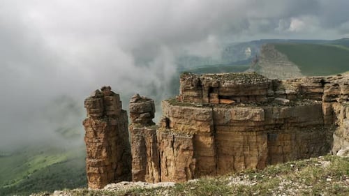 Misty rocky mountains surrounded by big thick fog.