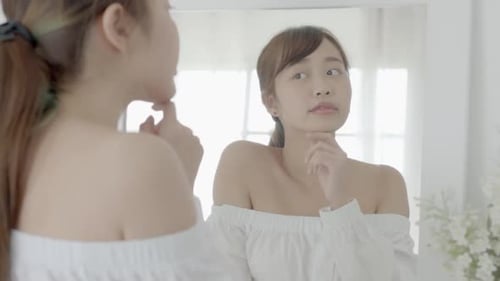 Beauty young asian woman smiling look at mirror of checking skin care caucasian with wellness.