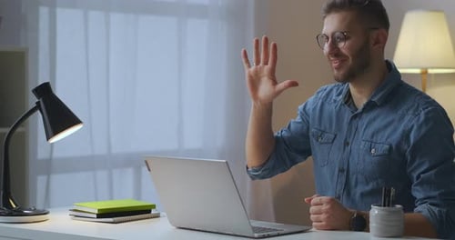 Man Waving During Video Call on Laptop