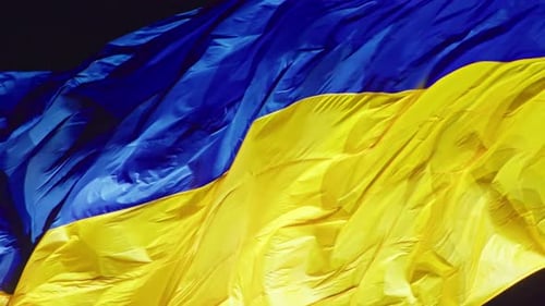 die Flagge der Ukraine Eine Seidenflagge weht vor dem Hintergrund des Nachthimmels auf einem großen Fahnenmast