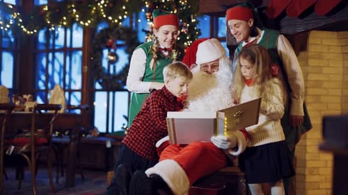 Santa Reading Glowing Book with Children and Elves