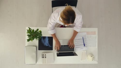 Young Pretty Female Doctor Working with Notebook in the Office