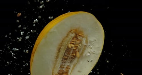La moitié du melon tombe sous l'eau avec des bulles d'air.