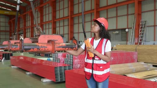 Jeune ingénieure testant et vérifiant le fonctionnement de la grue dans l'usine.