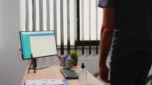 Masked Man Sanitizes Hands, Works at Office Computer