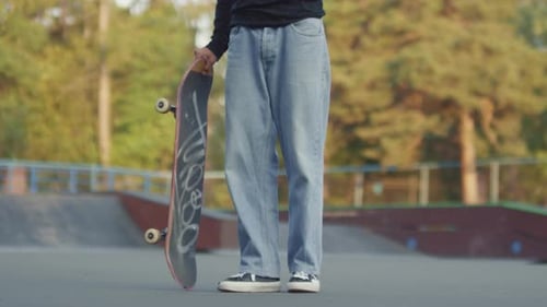 Young Person Holding Skateboard in Skatepark