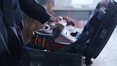 Woman Places Violin into Case at Home