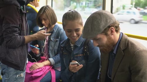 Young Adults Riding Bus with Phones and Tablets